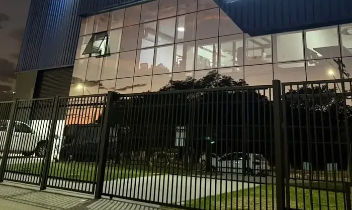 Fachada de um prédio comercial em estrutura metálica com fechamento em chapa e pele de vidro, à noite